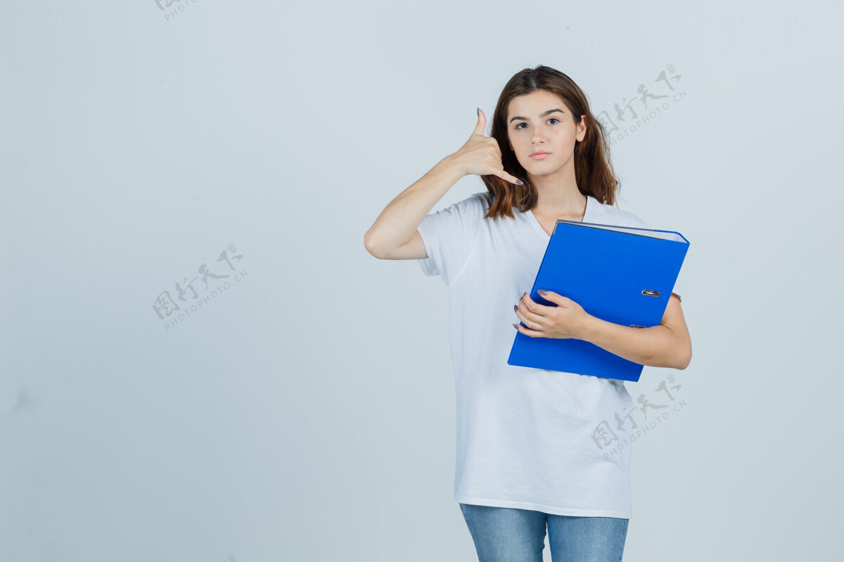 女人穿着白色t恤的年轻女孩拿着文件夹 展示着打电话的手势 看上去很有帮助 正面视图女孩年轻人漂亮