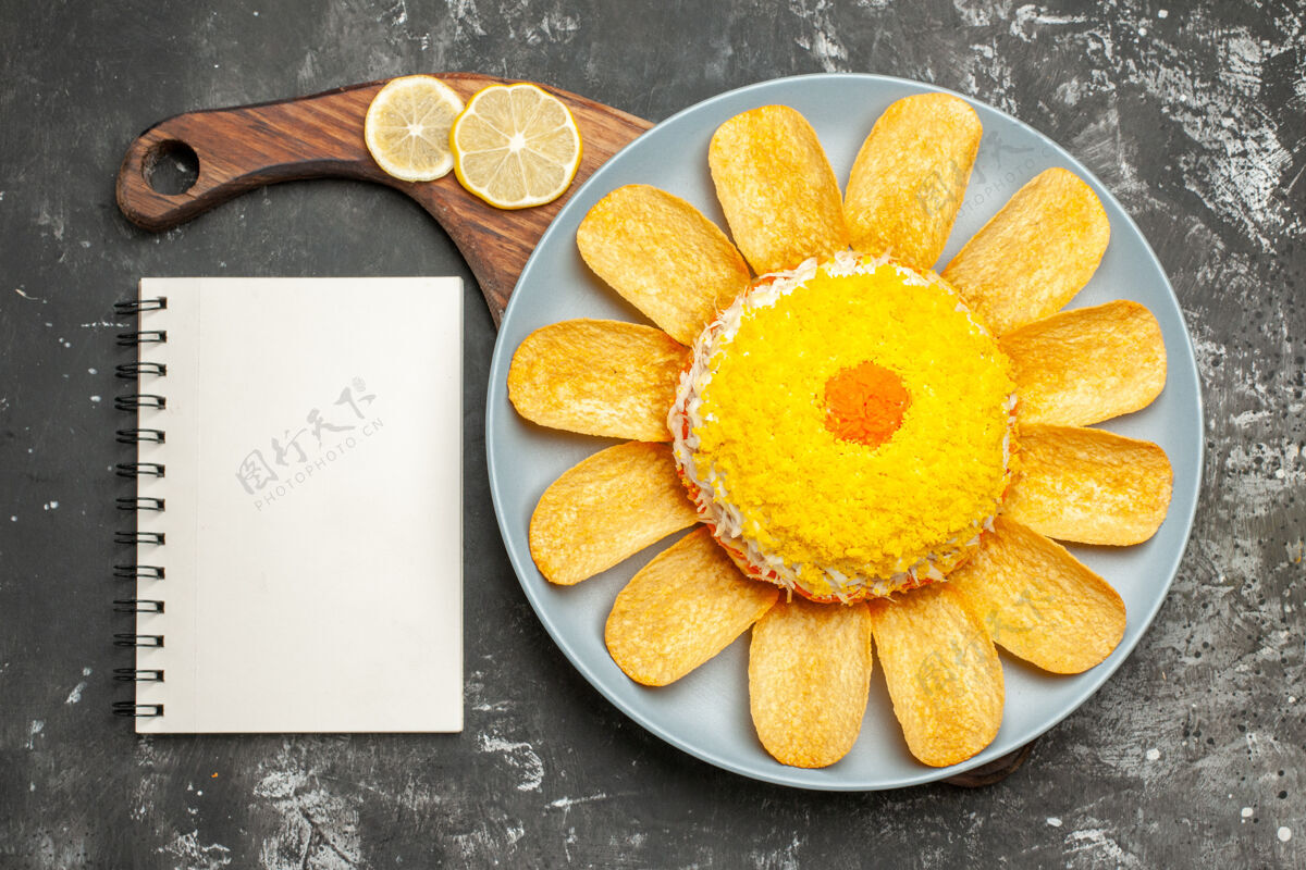 早餐沙拉的顶视图放在盘子架上 深灰色的桌子上 旁边放着柠檬和记事本健康支架盘子