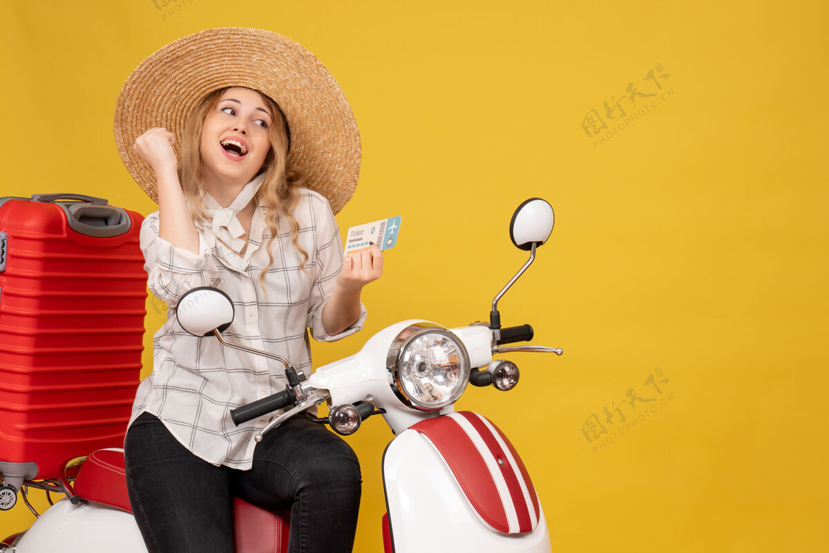 足球戴着帽子 坐在摩托车上 拿着黄色车票的快乐年轻女子的俯视图抱帽子足球