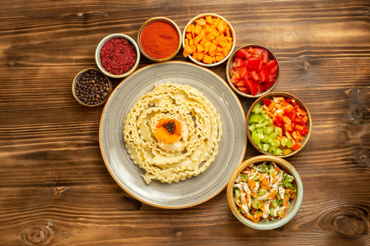 餐厅顶视图生面团由蔬菜和调味品在棕色桌上形成的生面团生面团美味面食午餐