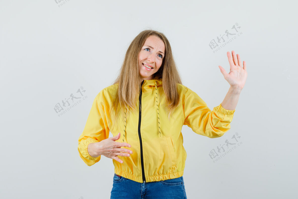 女性一位年轻的女士展示着停车标志 微笑着穿着黄色棒球服和蓝色牛仔裤 看上去很乐观正面图欢呼成人年轻