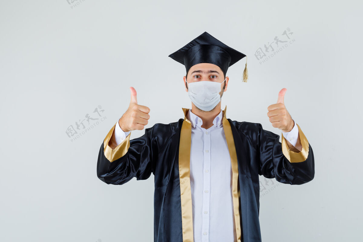 年轻身穿毕业制服的年轻人竖起大拇指 看上去很自信 正面照胡茬男人欢呼