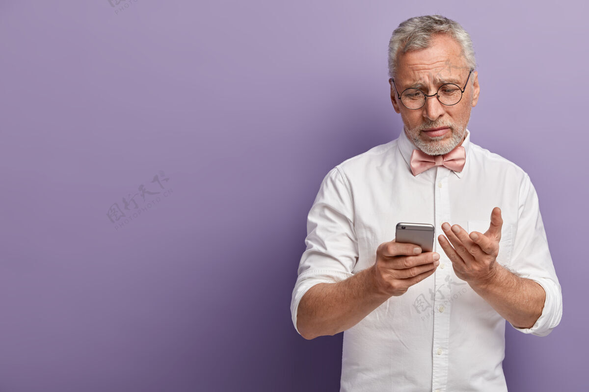电话穿着白衬衫和粉色领结的老人拿着电话衬衫男肖像