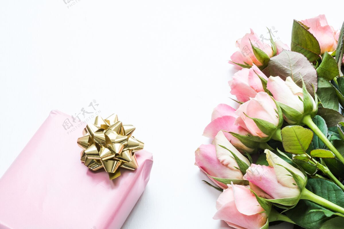 盒子用粉色纸包装的礼品盒 旁边有一束美丽的粉色玫瑰 上面有一条丝带正方形玫瑰礼品盒