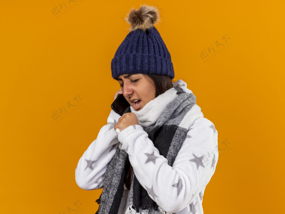 闭着咳嗽的年轻病女孩闭着眼睛戴着冬天的帽子 手拿围巾 嘴巴被隔离在黄色的背景上眼睛女孩围巾