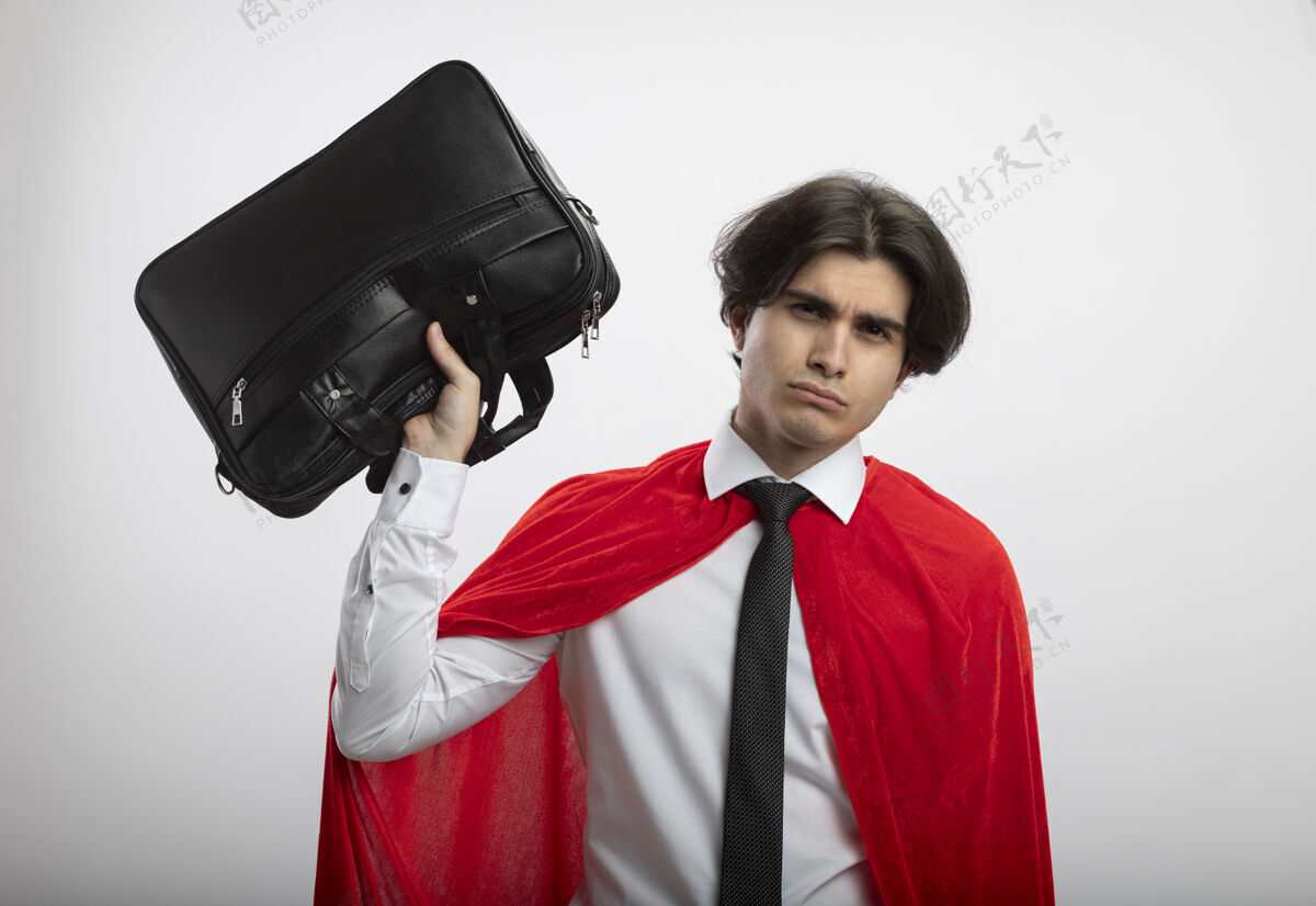 领带一个年轻的超级英雄 戴着一个白色背景的提包 看着摄像机男人超级英雄相机