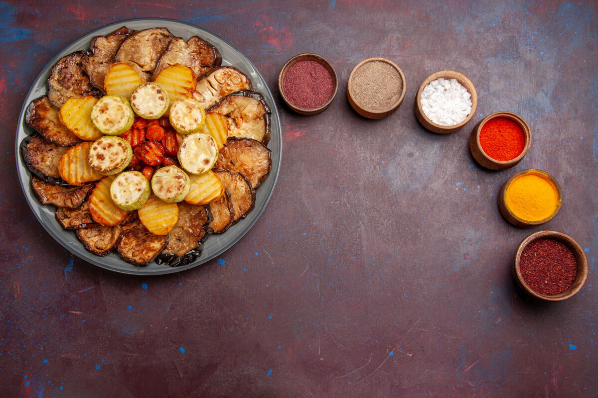 早餐顶视图烤蔬菜土豆和茄子与黑暗空间不同的调味品开心果烘焙午餐