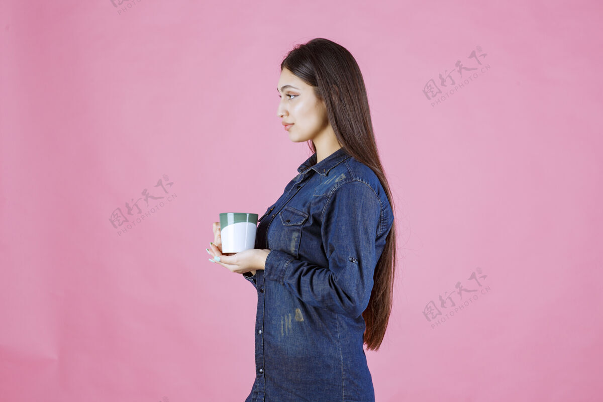 成人年轻女子拿着一个白绿色的咖啡杯 闻着姿势休闲女人