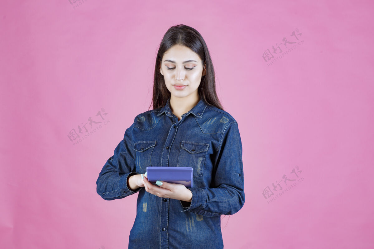 姿势年轻的女人手里拿着一个蓝色的计算器在计算现金金钱成人