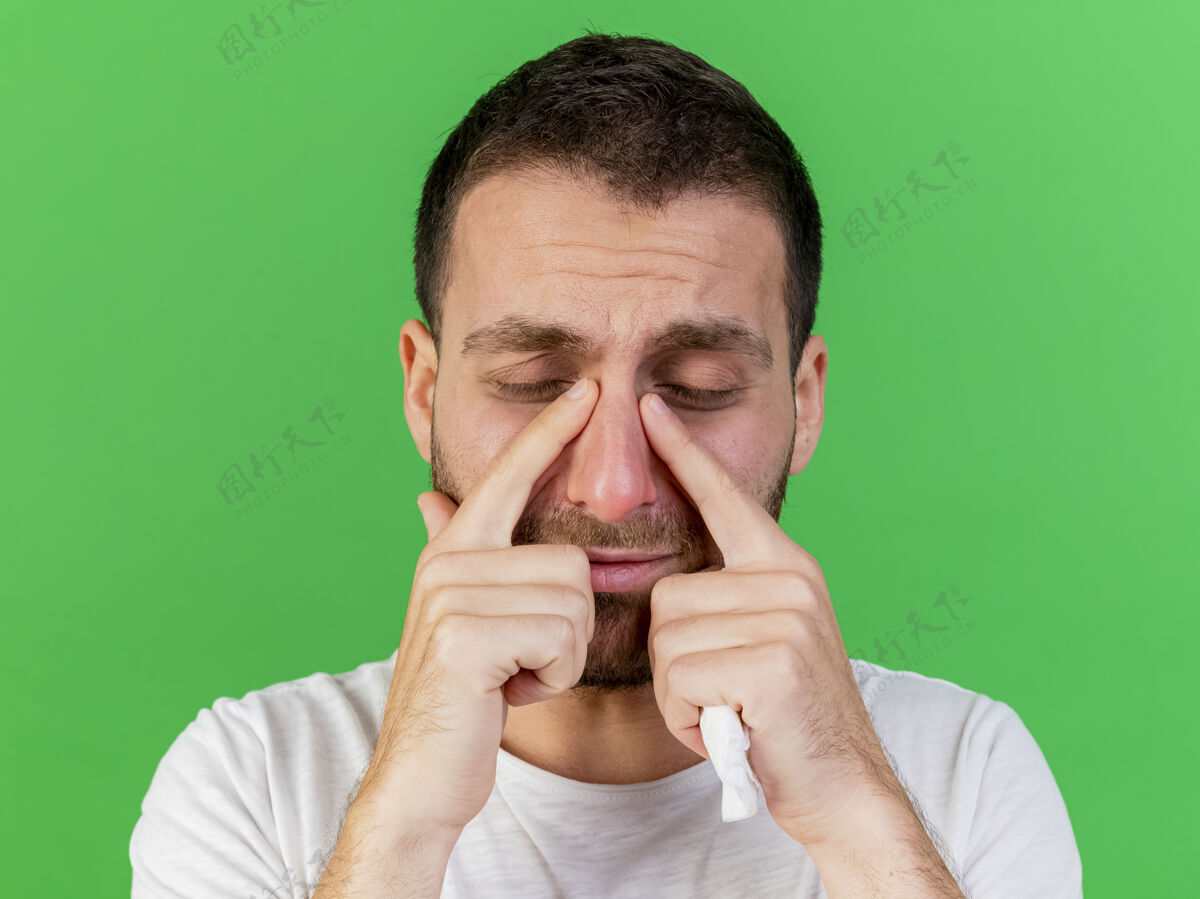 湿巾闭上眼睛悲伤的年轻病人用手指在绿色背景上擦拭眼睛手指眼睛年轻