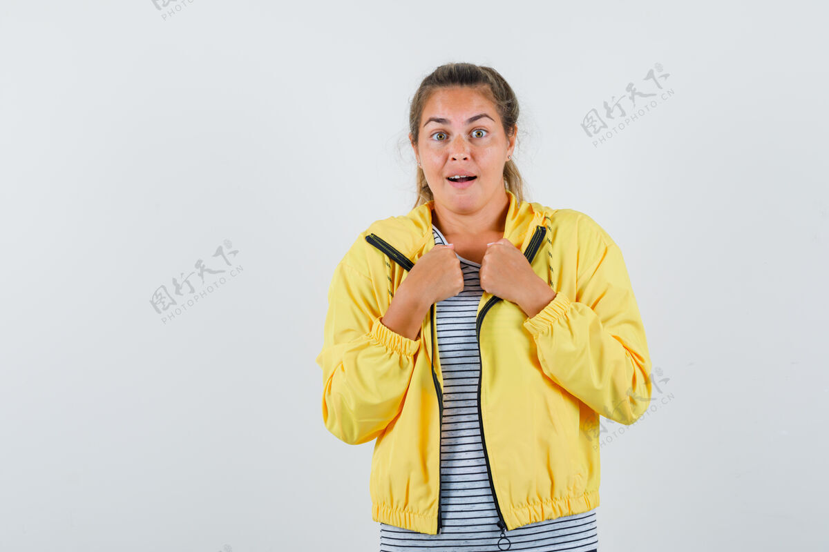 成人穿着黄色棒球服和条纹衬衫的金发女人握紧拳头 看上去很惊讶女性拳头黑发