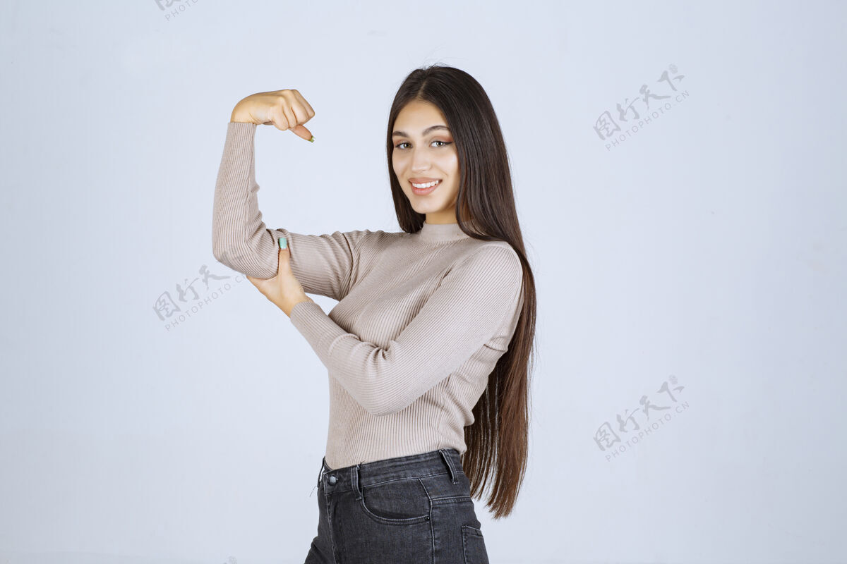 人体模特穿灰色毛衣的女孩展示她的拳头和力量员工休闲力量