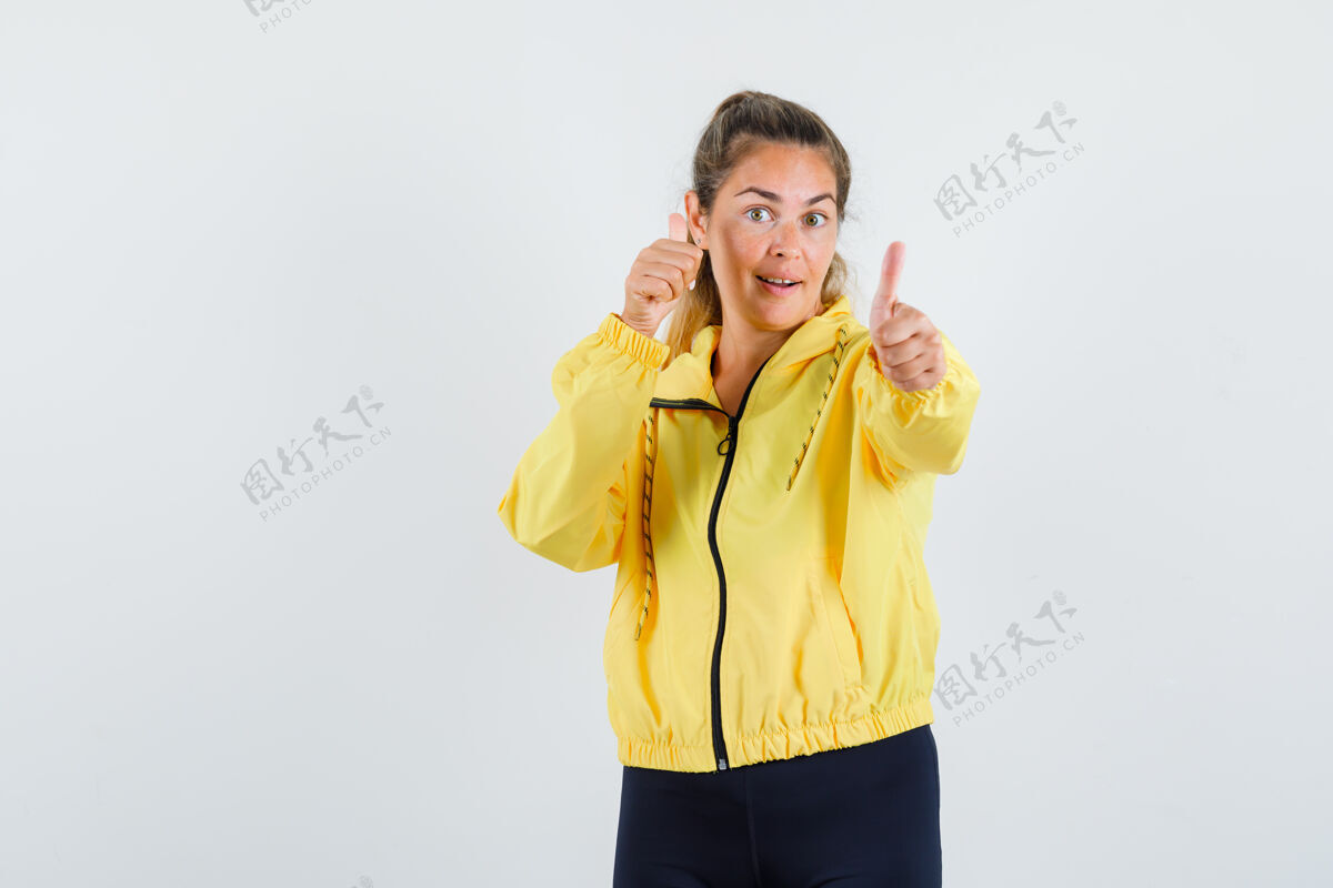 脸穿着黄色棒球服和黑色裤子的金发女人向上竖起大拇指 看起来很开心新鲜肖像干净