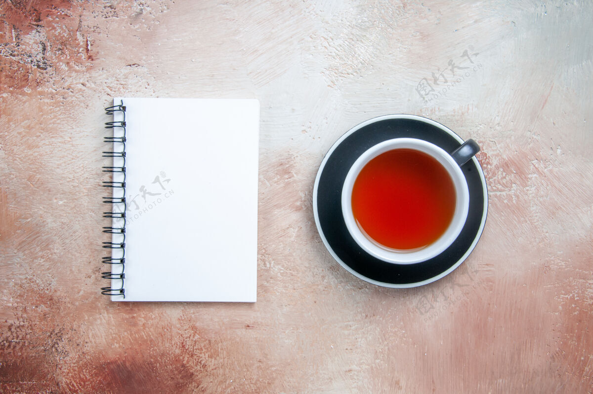 按钮从远处俯瞰一杯茶一杯茶在红碟白笔记本上马克杯茶咖啡因