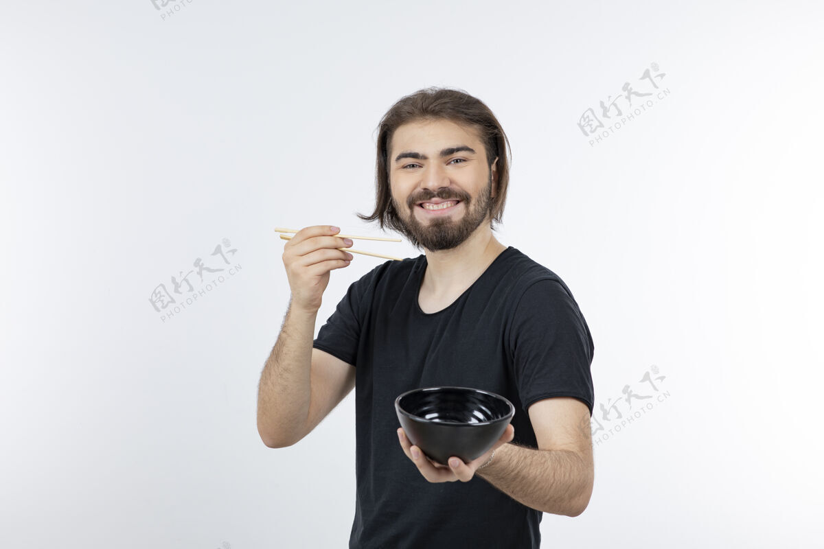 男性一个留胡子的男人拿着筷子在白色的墙上拿着碗年轻人模型摆姿势