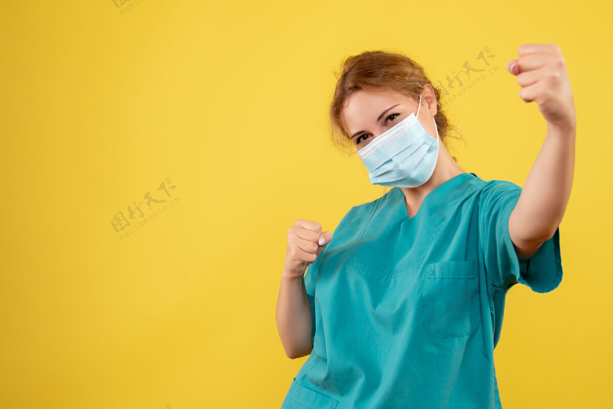 护士身着医疗服 戴着无菌口罩的年轻女医生在黄墙上欢呼雀跃的正面图绝育支持成人