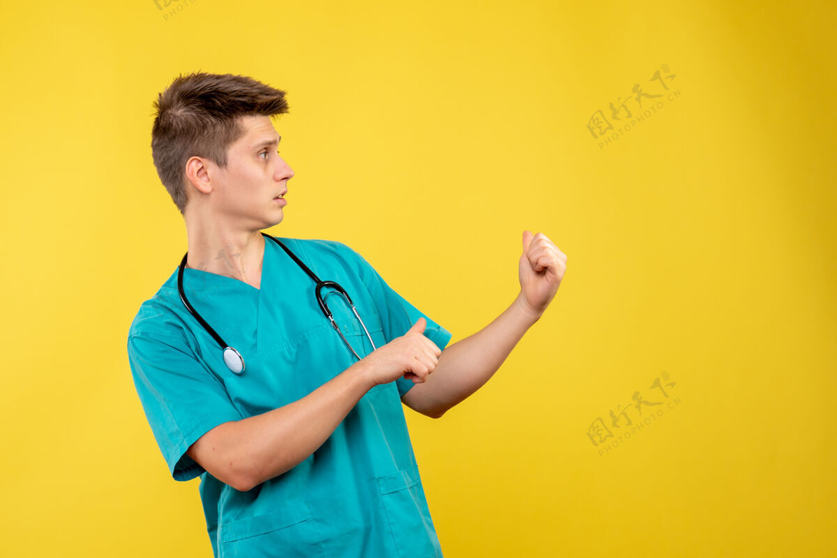 医院黄色墙壁上穿着医疗服 带听诊器的男医生的正视图成人男性健康
