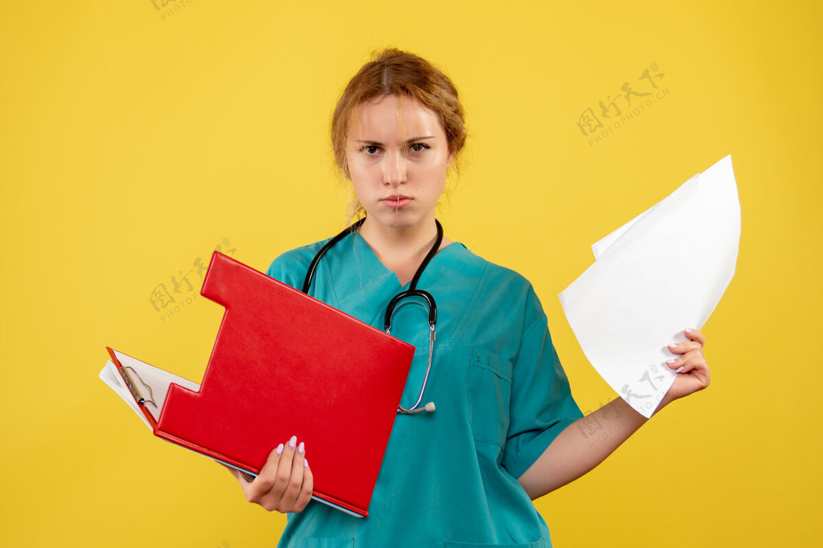 护士黄色墙壁上的女医生穿着医疗服 带着论文和分析的正视图分析西装纸张