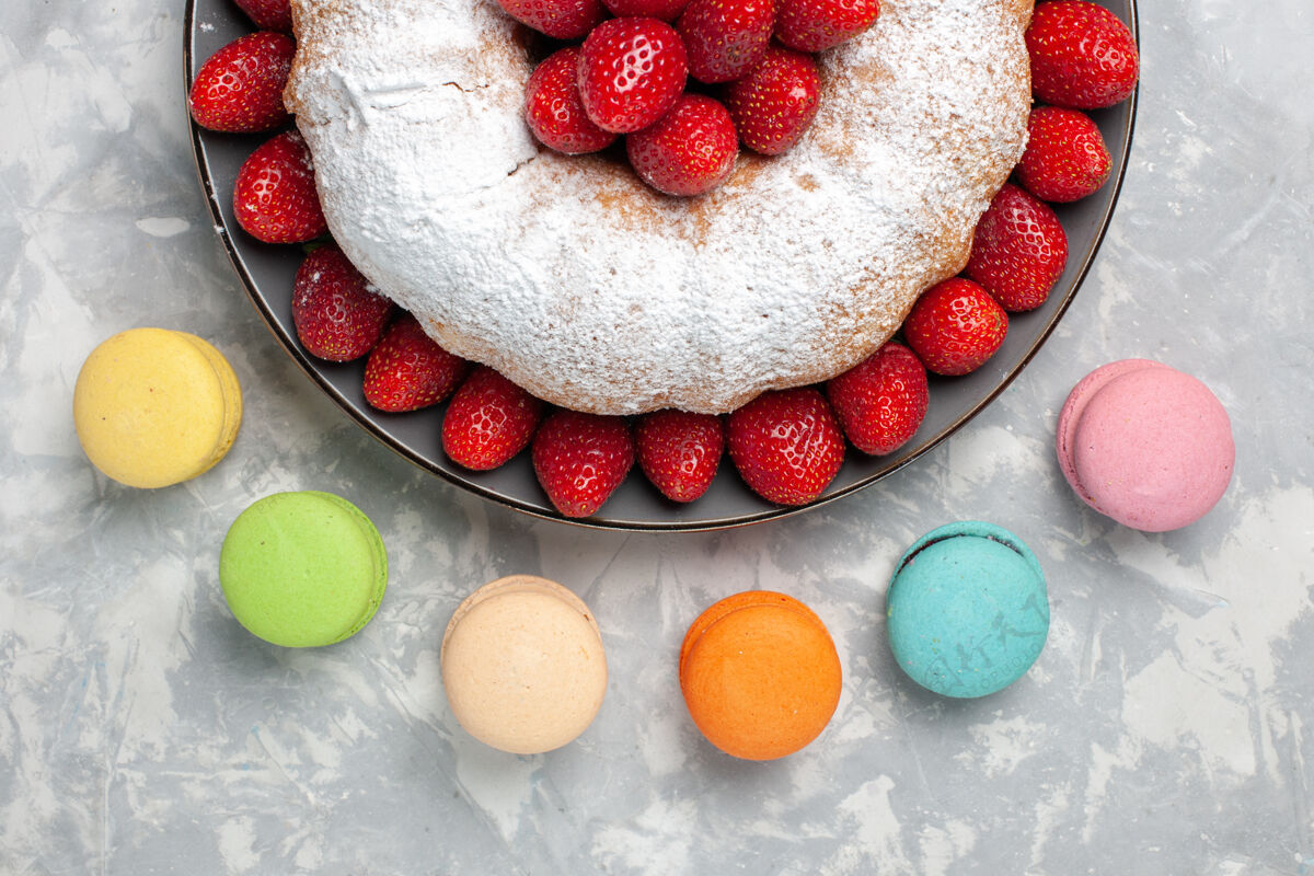 圆形俯瞰美味的草莓派和法国马卡龙在白色蛋糕巧克力草莓