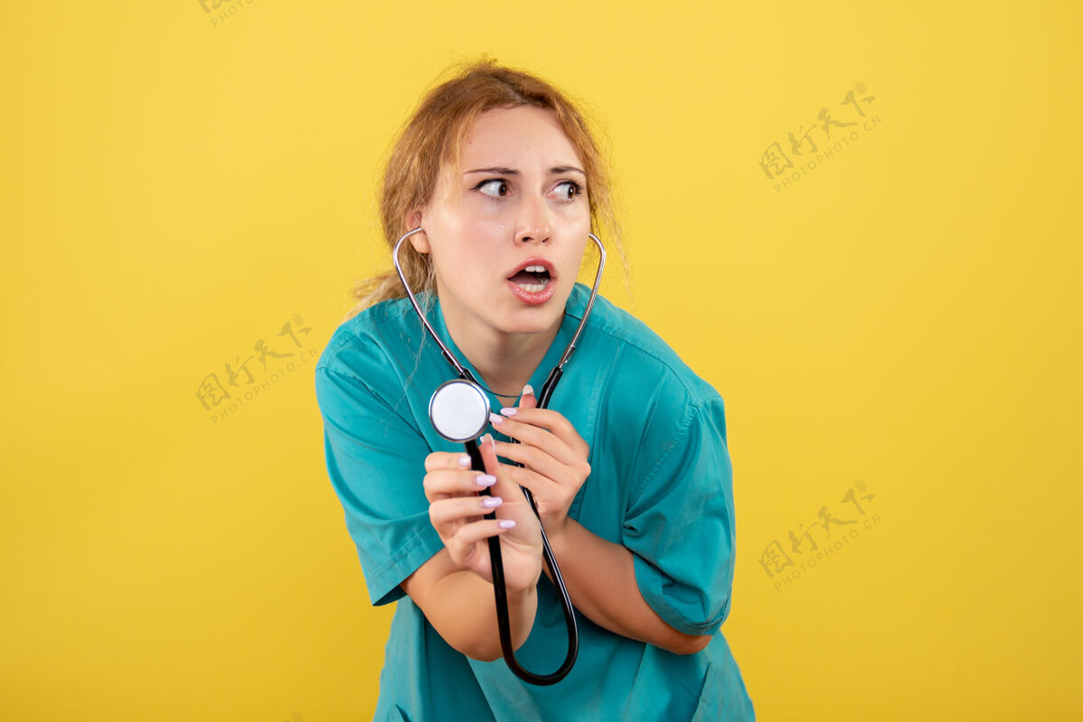 药品黄色墙壁上穿着带听诊器的医用衬衫的女医生的正视图仪器医疗衬衫