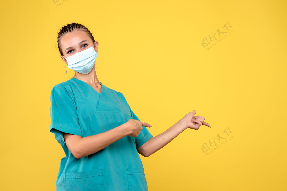 绝育黄色墙壁上穿着医疗服 戴着无菌口罩的女医生的正视图套装快乐人