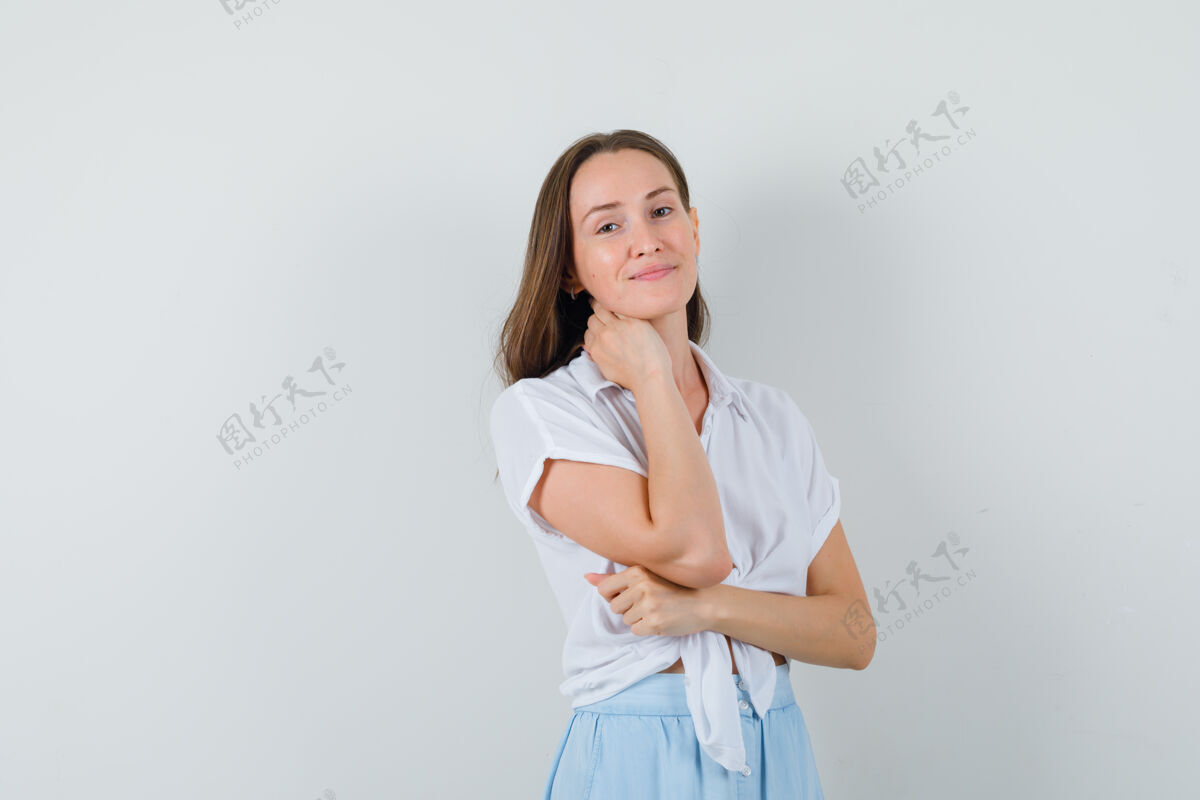 衬衫一位年轻的女士手挽着脖子 微笑着穿着白色上衣和浅蓝色裙子 看起来很迷人头发模特干净