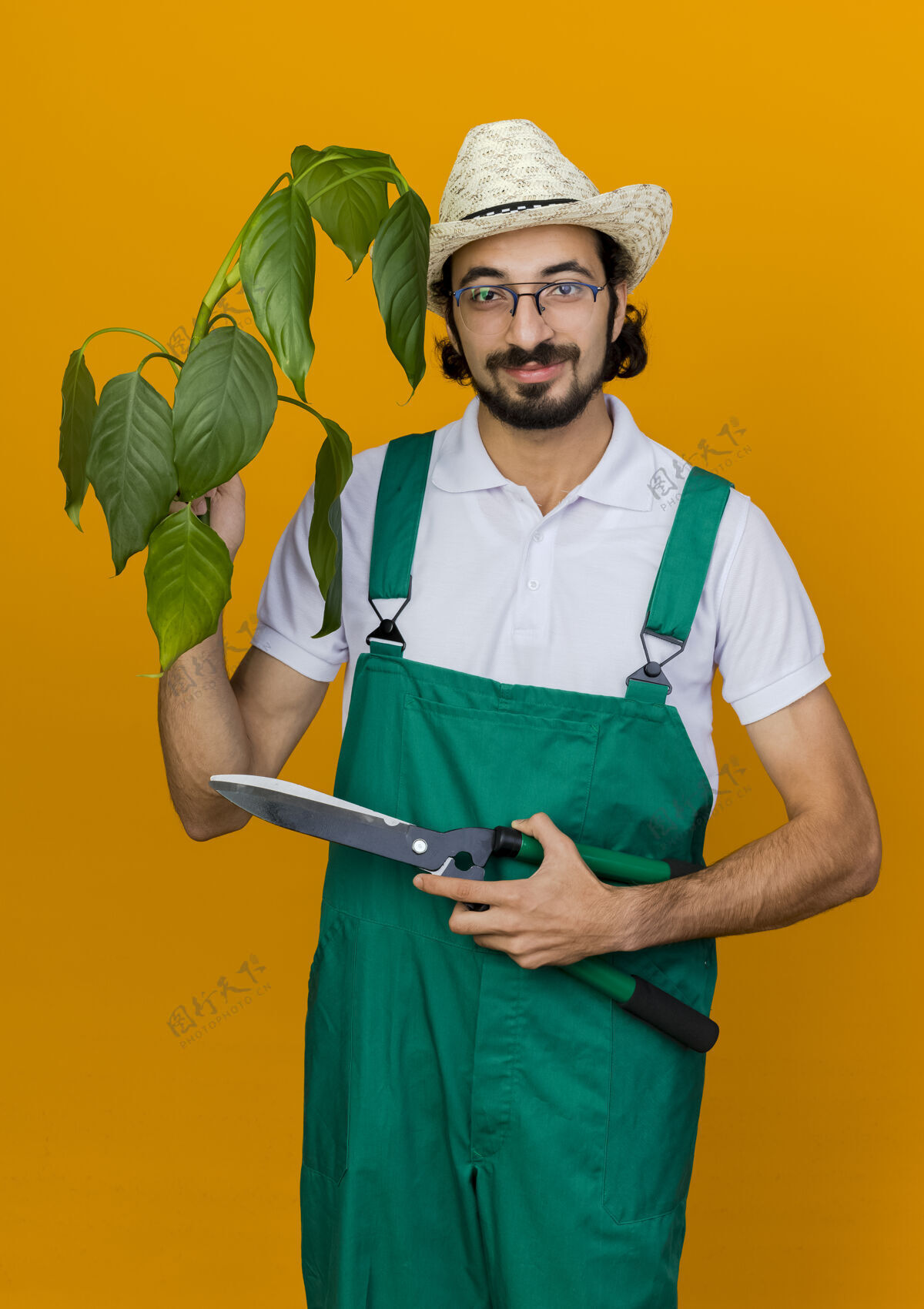 园艺高兴的男园丁戴着眼镜戴着园艺帽拿着植物和剪子空间复制眼镜