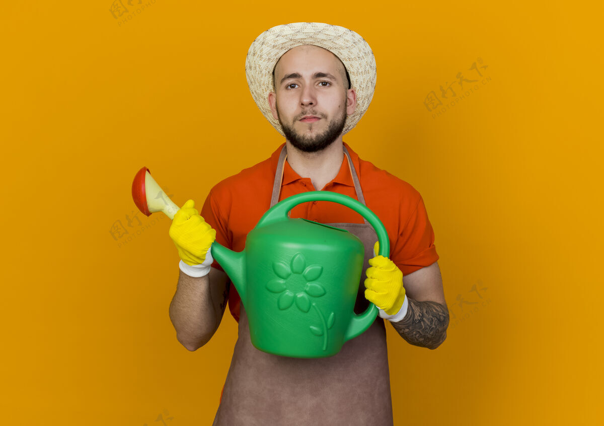 园艺自信的男园丁戴着园艺帽拿着浇水罐看信心帽子橙色