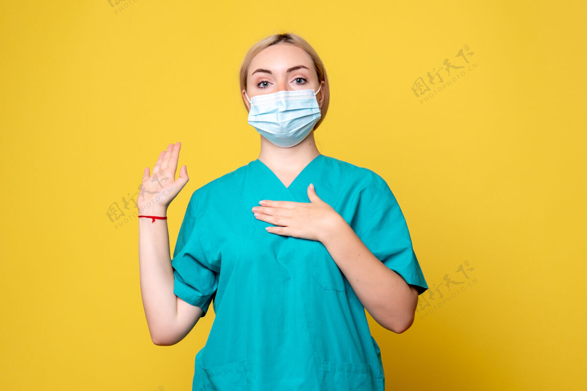 年轻女医生黄墙上年轻女医生穿着医用衬衫 戴着口罩的正面图流行病人脸