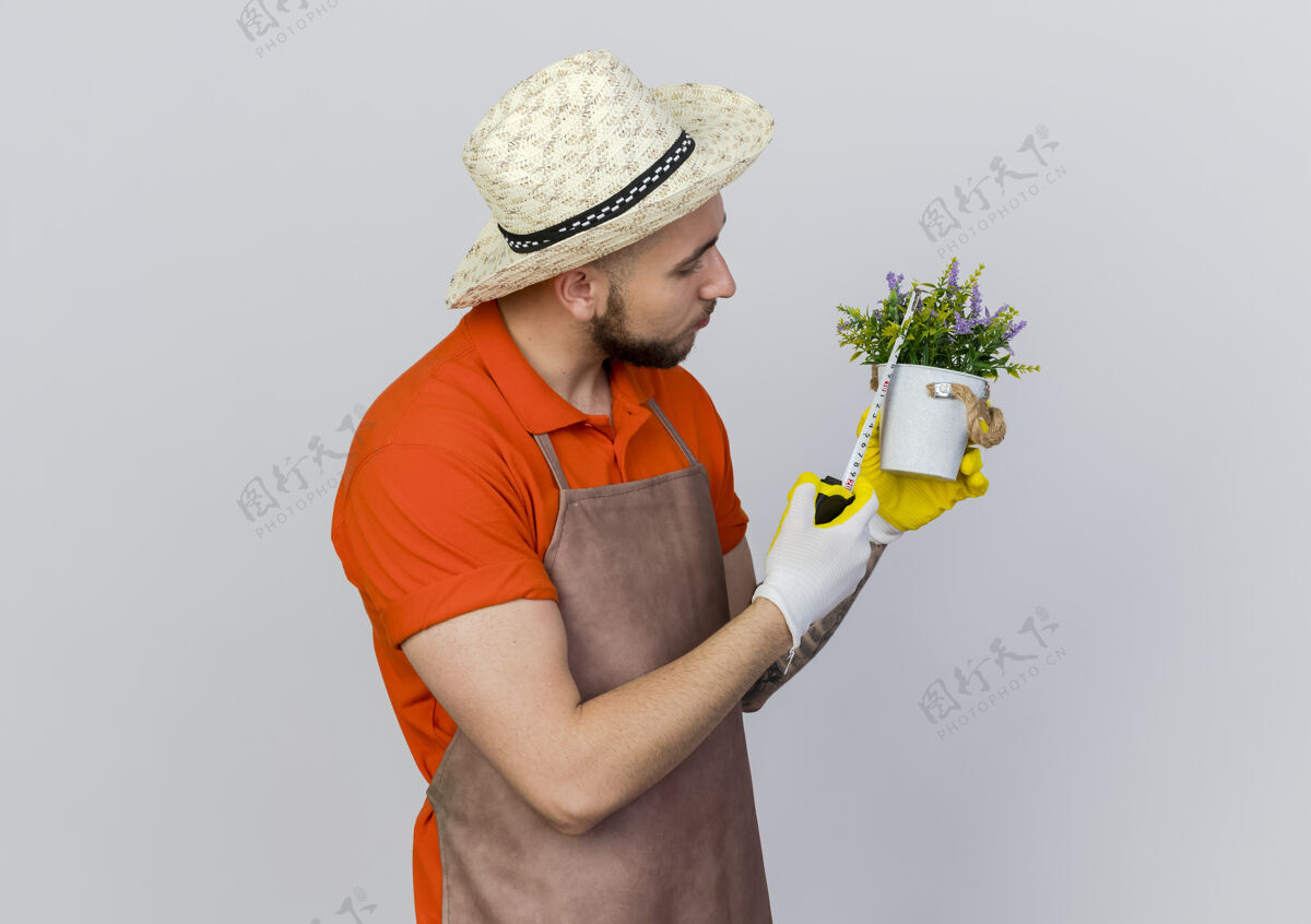 信心自信的男园丁戴着园艺帽用卷尺量花盆空间花盆花园
