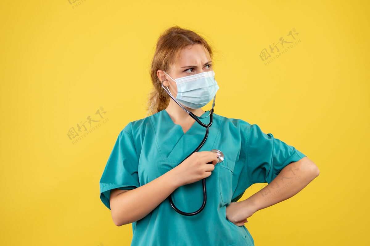 正面黄墙上穿着医疗服 戴着听诊器面罩的女医生的正视图听诊器器械健康
