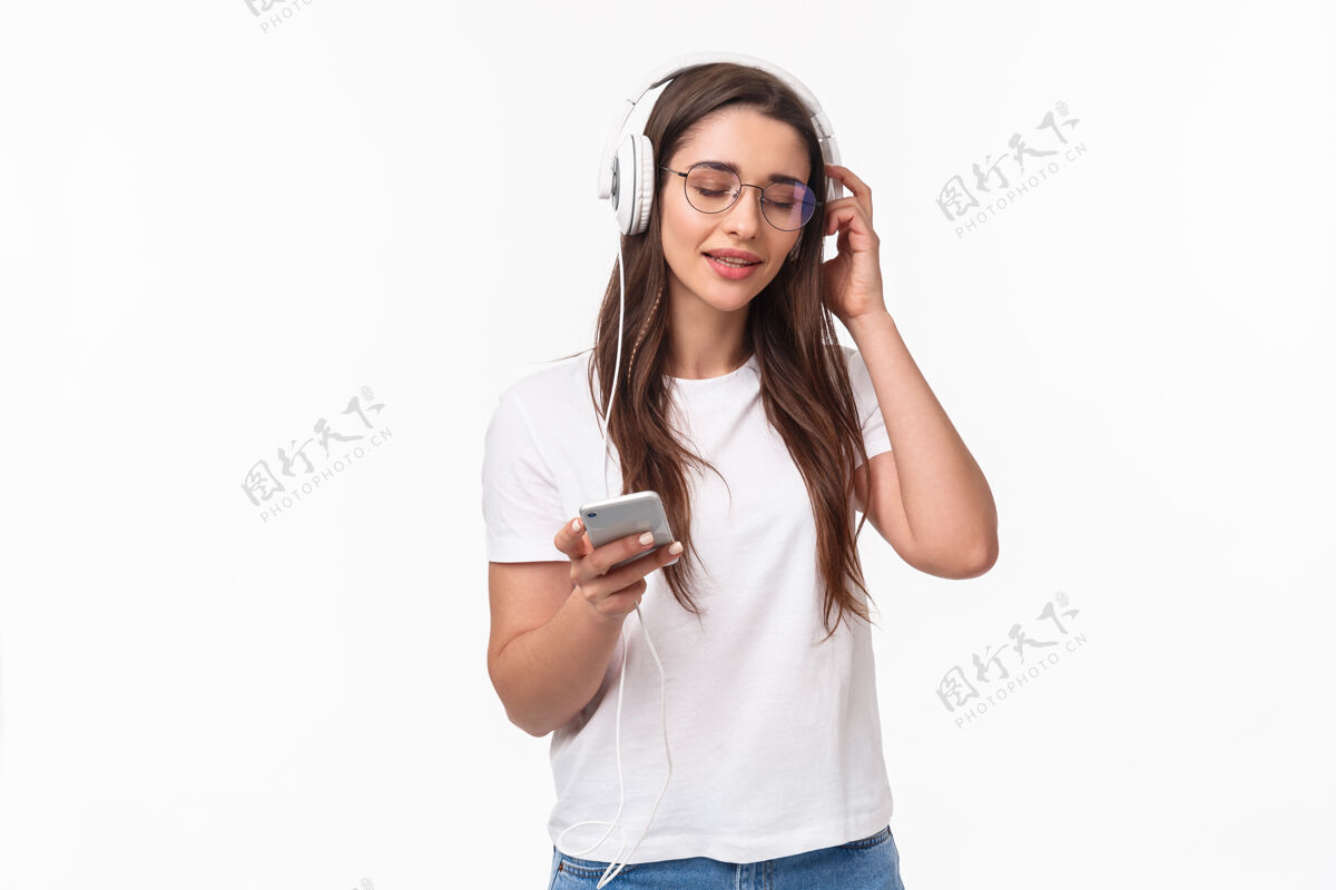 女人一位富有表现力的年轻女子手持手机聆听音乐美丽微笑女孩