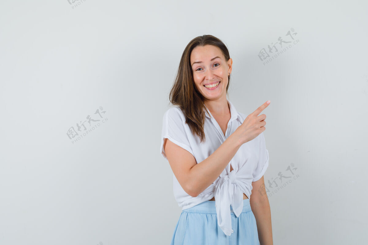 右穿着白衬衫和淡蓝色裙子的年轻女子用食指指着右边 看上去很高兴清洁快乐指