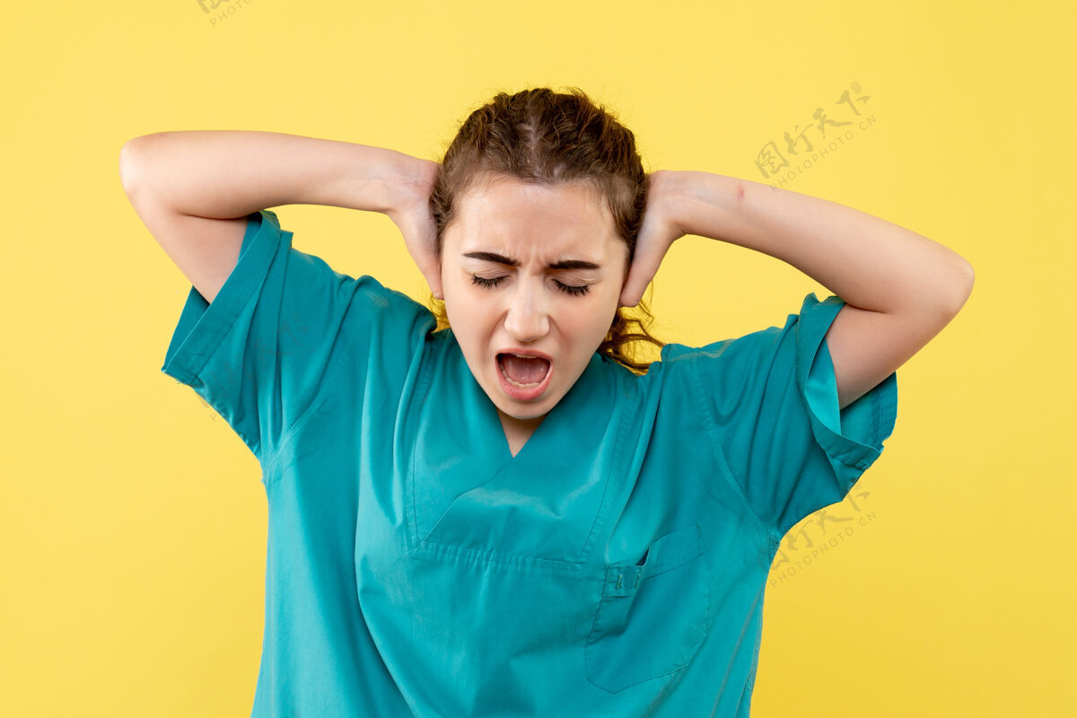 病毒身着医疗服的年轻女医生在黄墙上闭上耳朵的正面图休闲人年轻女医生