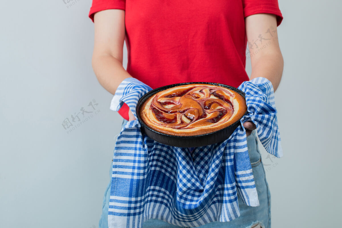 人体模型穿红衬衫的年轻女孩手里拿着一个黑平底锅里的馅饼工作人员成人糕点
