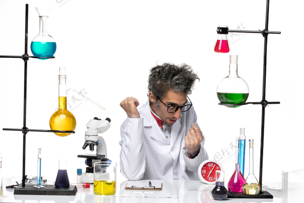 套装前视图穿着医疗服的男科学家坐在桌子前 用白色背景的解决方案-实验室病毒健康化学医学前面研究