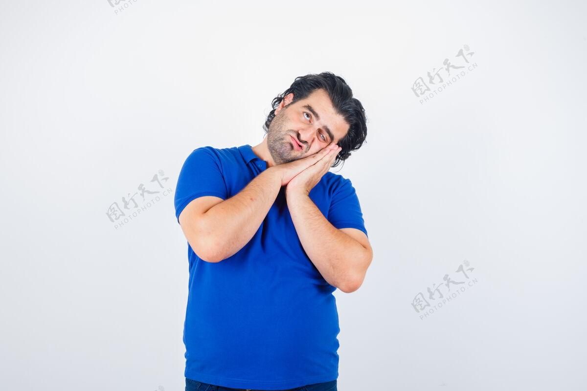 成功成熟的男人斜靠在手掌上作为枕头 穿着蓝色t恤 看上去很体贴 前视图前面思考胡须