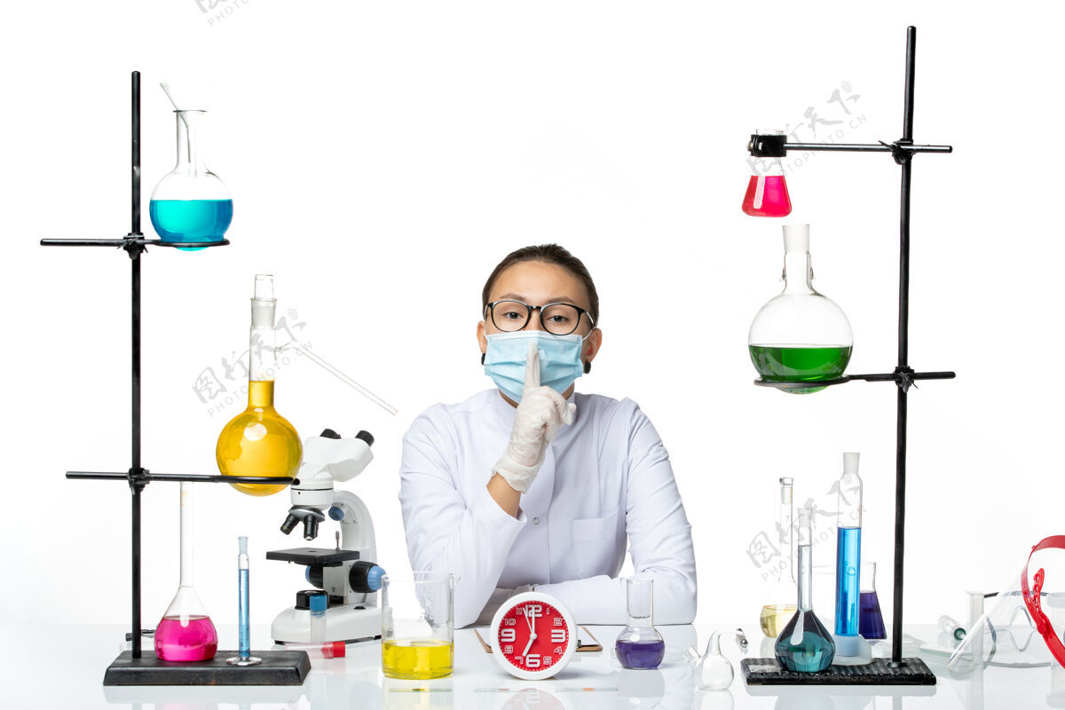 西装前视图穿着白色医疗服的女化学家带着面罩坐在白色背景上的溶液化学家实验室病毒-飞溅医学病毒医生