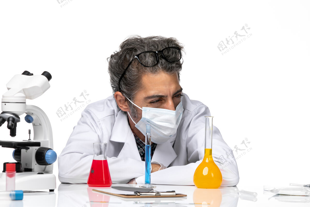 病毒正面近距离观察身着特殊套装的中年科学家 坐在白色背景上 用溶液溶解男性病毒科学病毒-化学科学化学解决方案