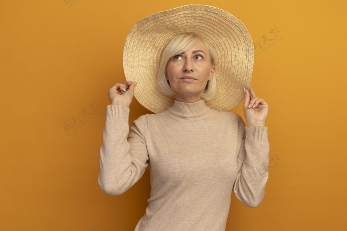 帽子戴着沙滩帽的漂亮金发斯拉夫女人抬起头看着橙色金发女人时尚