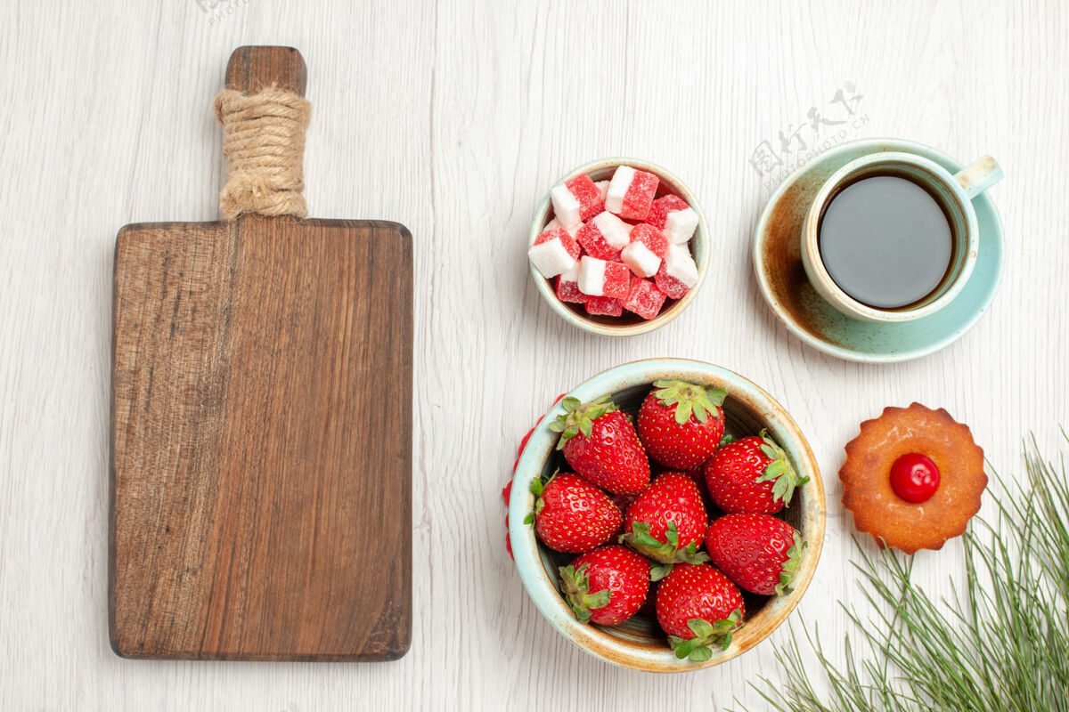 茶俯瞰图：白色桌子上有水果蛋糕和一杯茶杯子多汁草莓