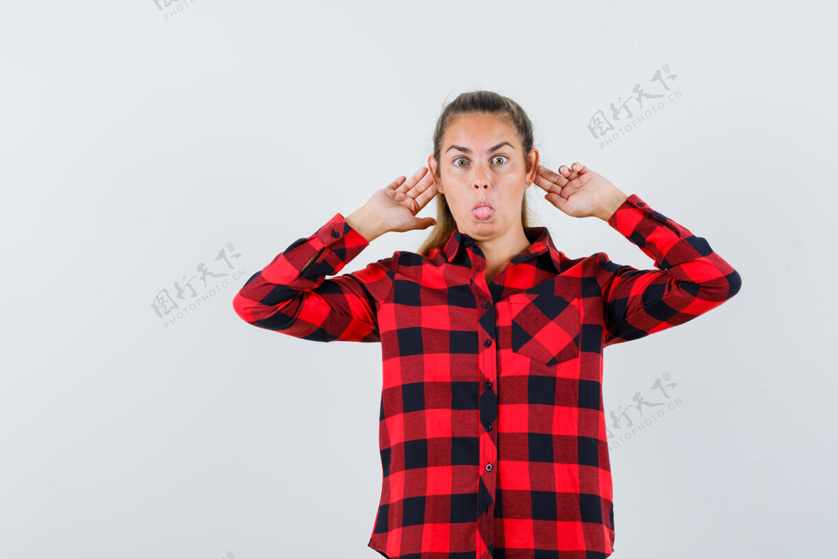 搞笑穿着休闲衬衫的年轻女士把手指放在耳朵后面 看起来很有趣 正面视图女性休闲年轻