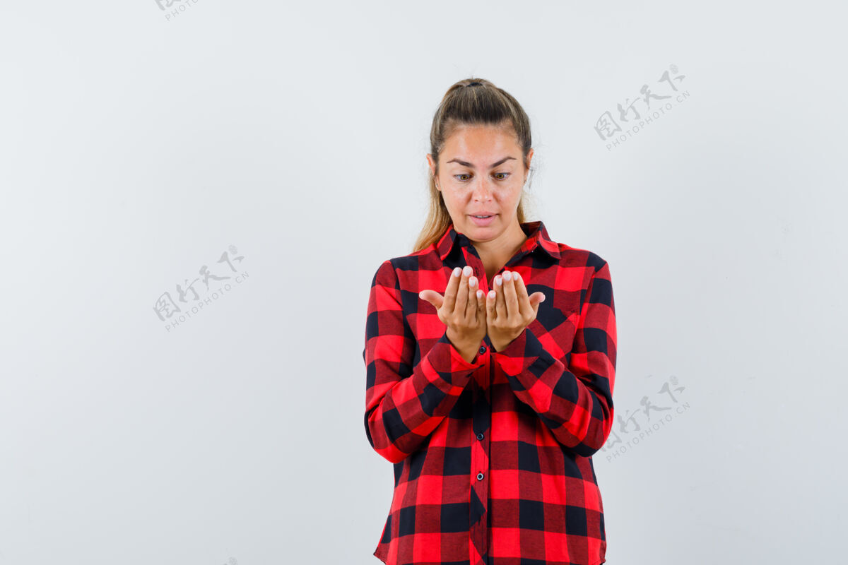 脸年轻的女士看着她穿着休闲衬衫的双手 看起来很惊讶前视图肖像手衬衫