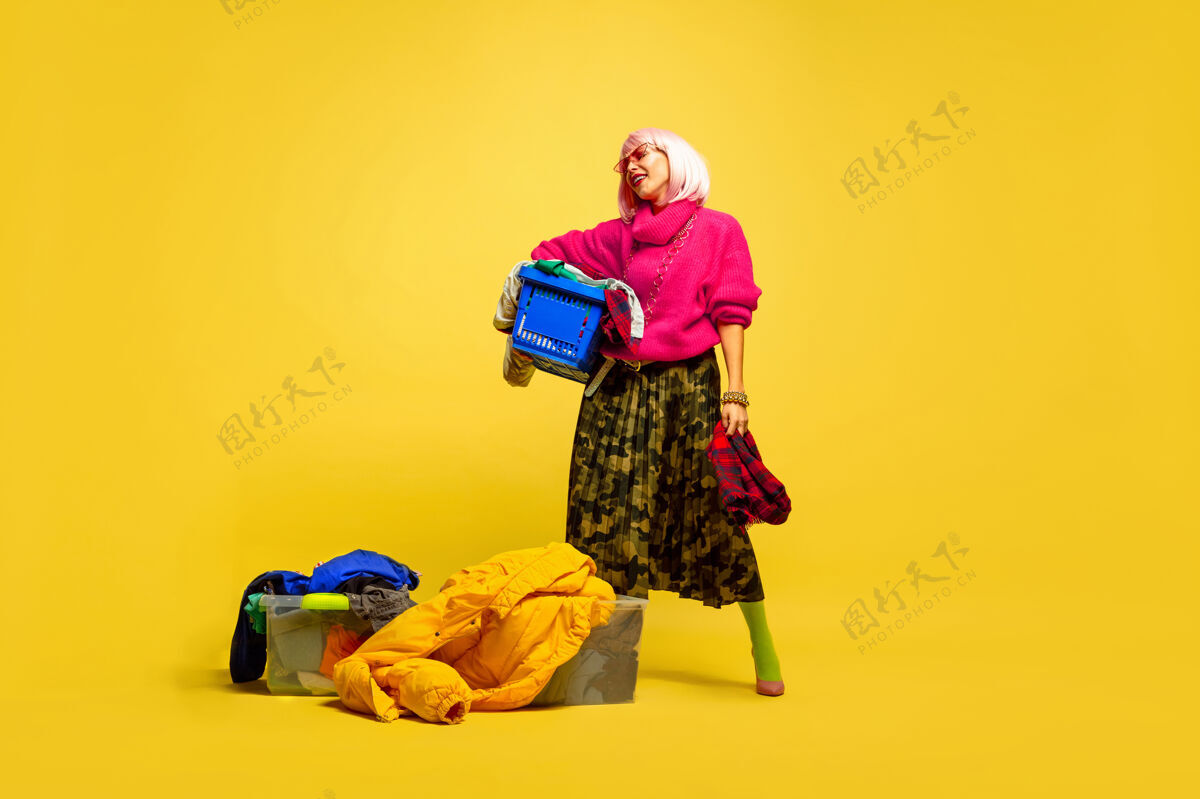 手较长的洗衣房和收集的衣服白人妇女的肖像在黄色背景上市场营销工作商业