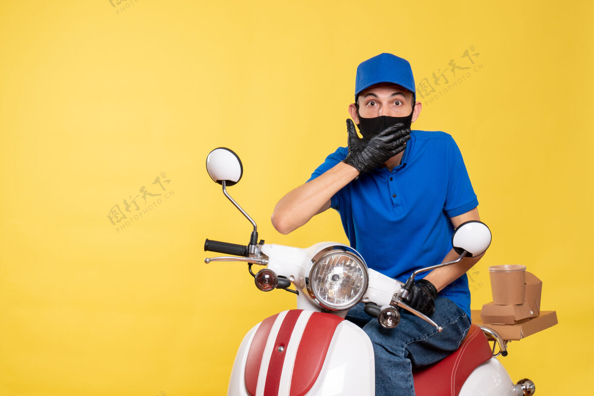 球正面图身穿蓝色制服 戴着黄色自行车面罩的男性快递员柯维德-大流行快递工作病毒服务工作男球员自行车