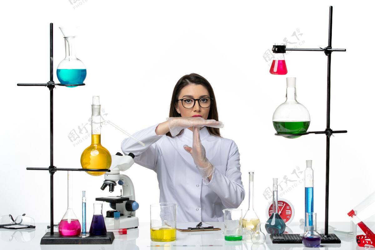 研究前视图穿着白色医疗服的女化学家正坐在白色背景的科学冠状病毒大流行实验室的解决方案人实验室视图