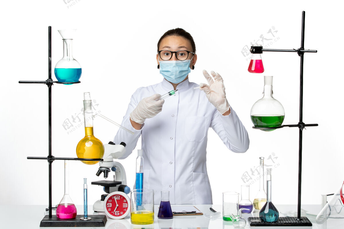 面具正面图白色背景病毒化学实验室covidsplash上穿着医疗服的女化学家戴着口罩拿着针剂科学视图前面