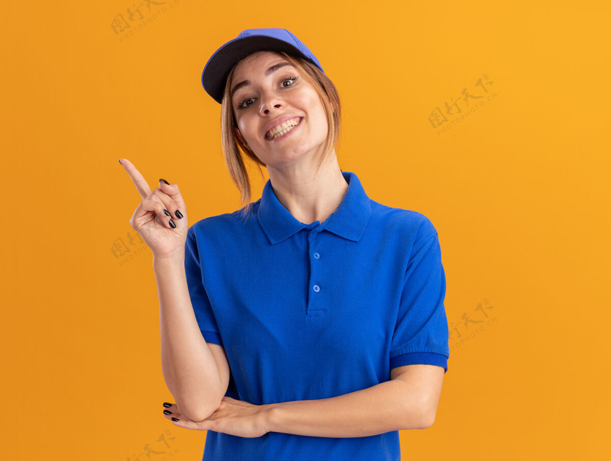 年轻微笑着的年轻漂亮的送货女孩在制服点边上橙色侧线制服姿势