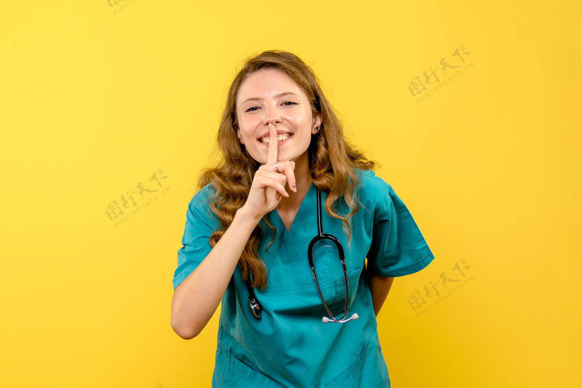 黑发黄色墙上微笑的女医生的正面图情感可爱听诊器