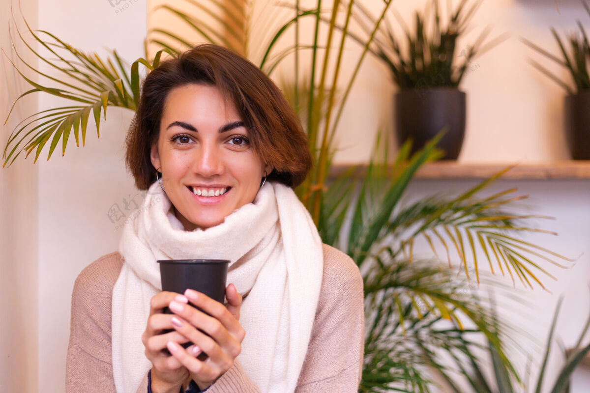 女人一个女孩在舒适的咖啡馆里用一杯热咖啡取暖年轻成人微笑